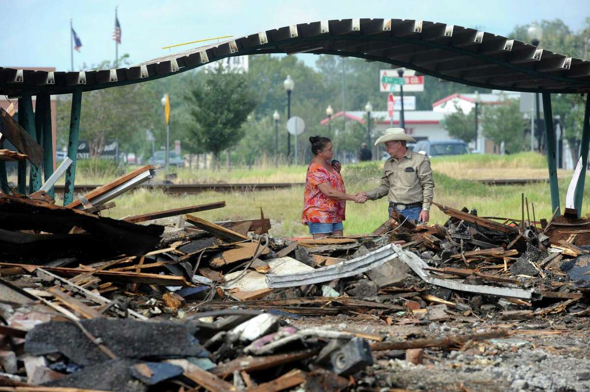 Mary Beth Segree, a former Pig Stand employee, and Richard Behnken, the demolition director of the Pig Stand, shake hands during the famed building's demolition on Tuesday. Behnken gave Segree a piece of green tile found in the rubble. Photo taken Tuesday, October 11, 2016 Guiseppe Barranco/The Enterprise