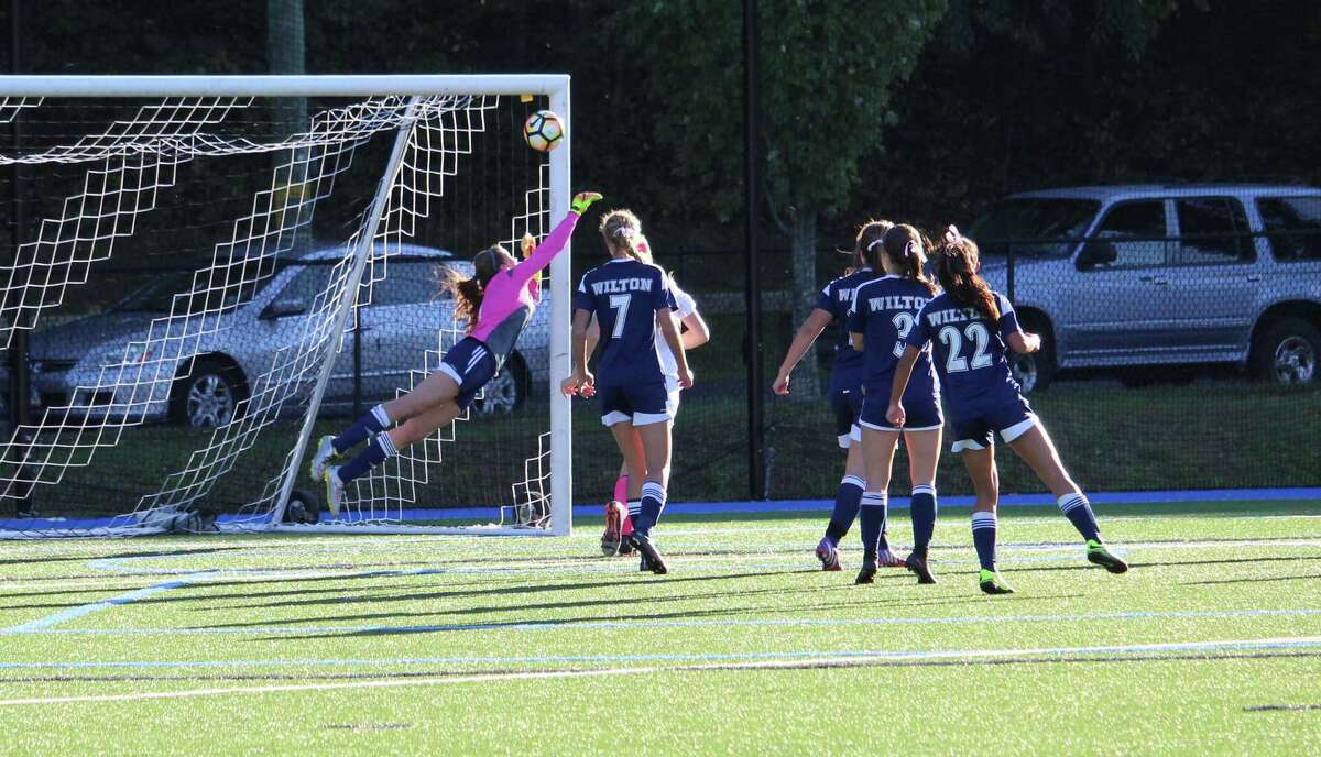 Wilton's Taylor Floyd goes full extension to turn away a Darien free-kick late in the first half. Floyd made eight stops in Wilton's 2-1 victory over the Blue Wave Tuesday at Darien High School.
