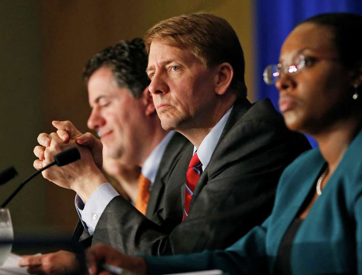 Consumer Financial Protection Bureau Director Richard Cordray, center, listens during a panel discussion in 2015. Some Republican lawmakers want him fired. ﻿