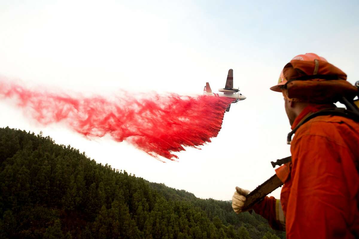 An inmate firefighter watches as an air tanker drops retardant while battling a wildfire near Morgan Hill, Calif., on Wednesday, Sept. 28, 2016. A growing and destructive wildfire moved toward remote California homes in the Santa Cruz Mountains on Wednesday as it scorched its way through bone-dry brush and trees. (AP Photo/Noah Berger)