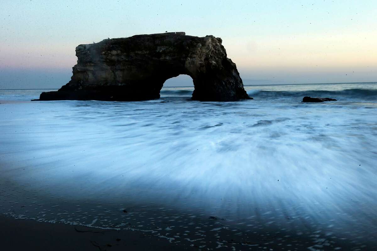 In this picture made with a long exposure, waves move on the shore as the sun sets at Natural Bridges State Beach in Santa Cruz.