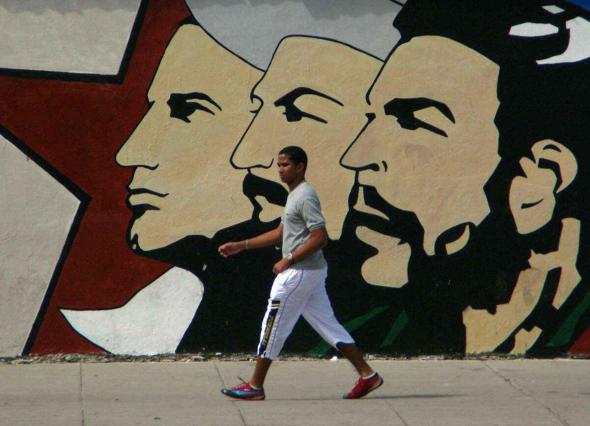 A Cuban man walks under the gaze of the leaders of La Revolucion, one of many murals meant to inspire patriotism. (Spud Hilton / The Chronicle)