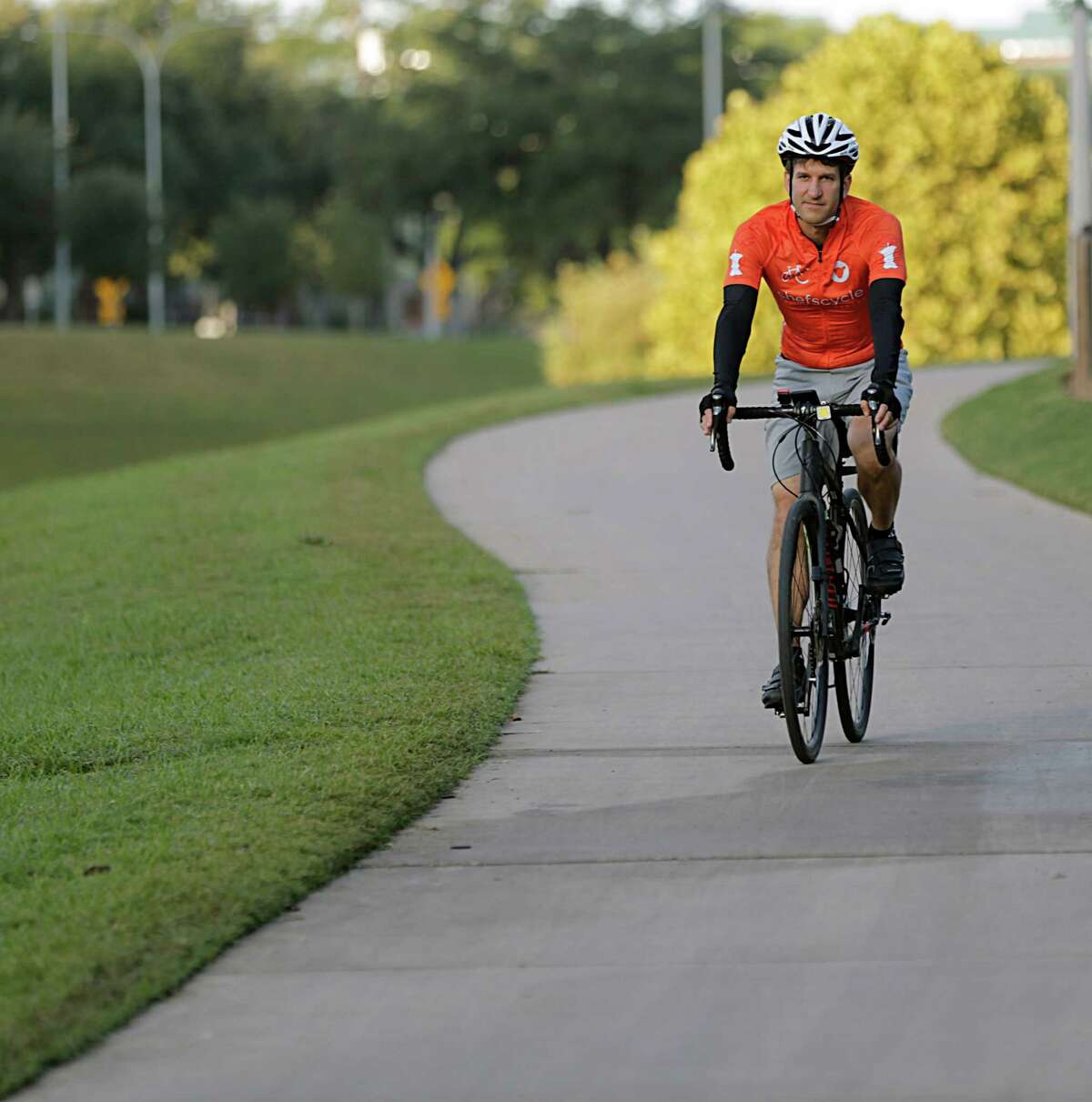 Ryan Pera poses for a portrait riding his bicycle on a trail in Buffalo Bayou Park on Oct. 12.