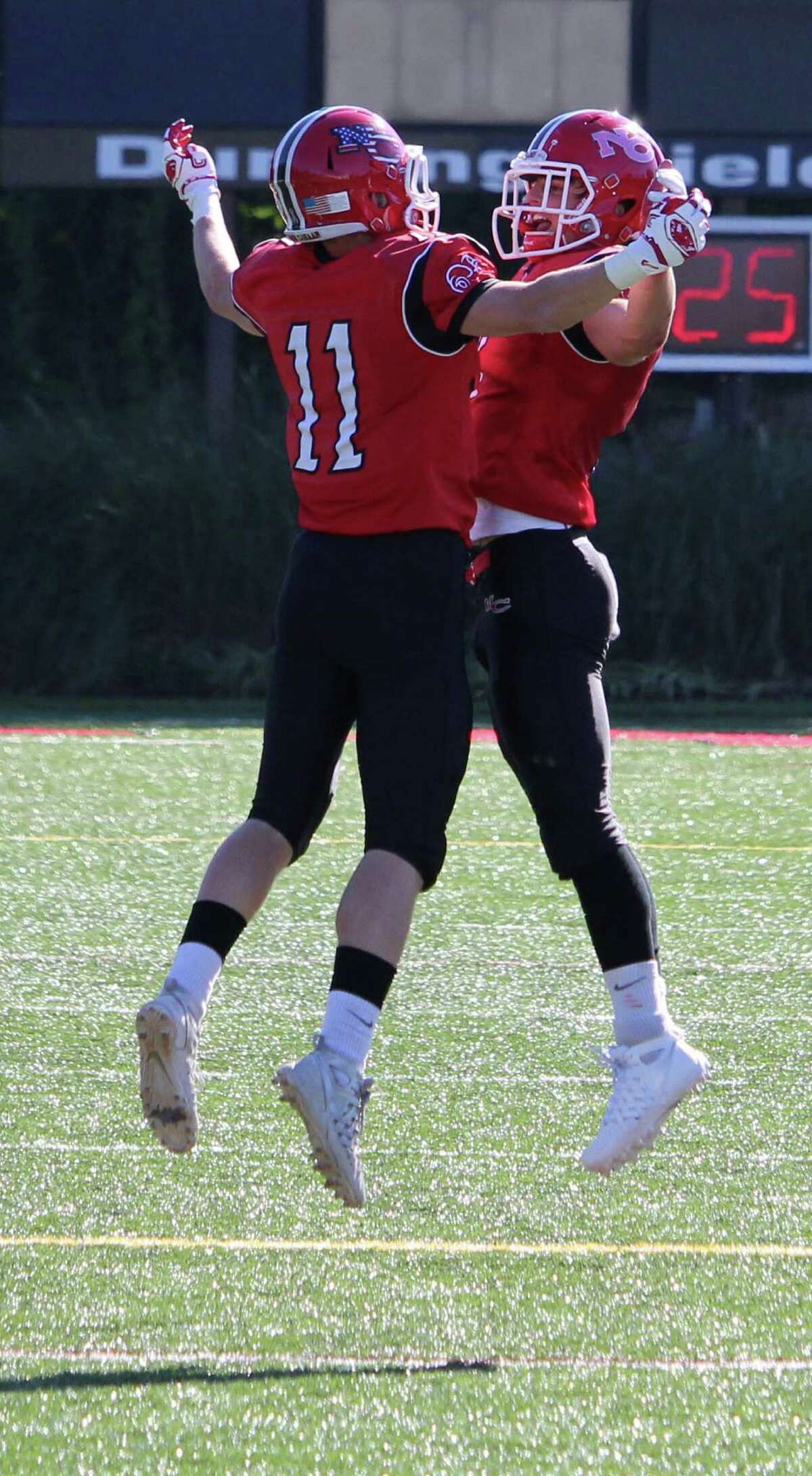 New Canaan’s Jack Hoelzer (11) and Ryan O’Connell celebrate after Hoelzer’s second quarter touchdown.