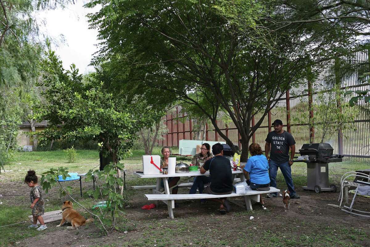 Members of the Grandos family grill in their backyard next to the border barrier in Brownsville. They’ve seen migrants scale the fencelike wall in less than a minute.