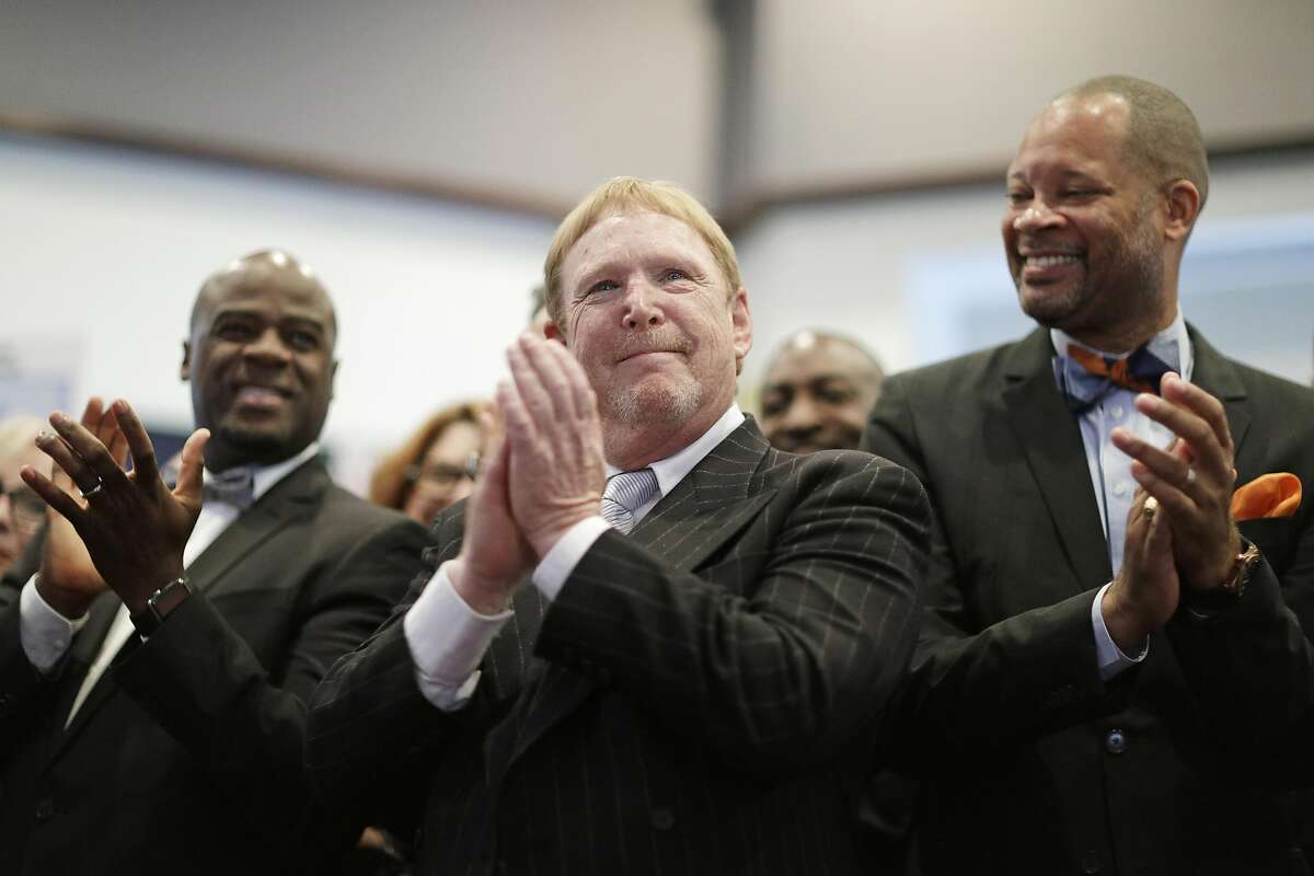 Oakland Raiders owner Mark Davis, center, claps as he attends a bill signing ceremony with Nevada Governor Brian Sandoval, Monday, Oct. 17, 2016, in Las Vegas. Sandoval signed a bill into law that clears the way for a Las Vegas stadium that could be home to both UNLV football and the Raiders. (AP Photo/John Locher)