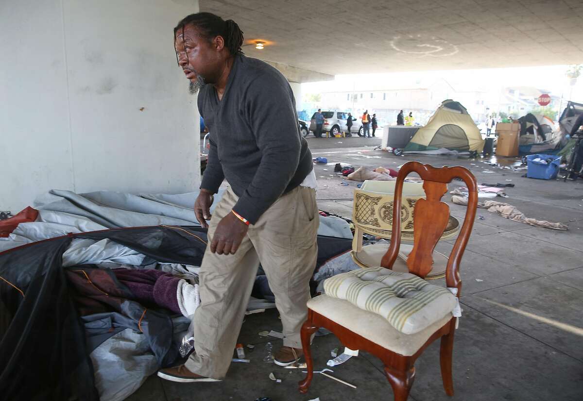 Campanella Martin (middle) helps move his friend's items from the homeless encampment on the island at 35th and Magnolia Streets on Monday, October 17, 2016, in Oakland, Calif.