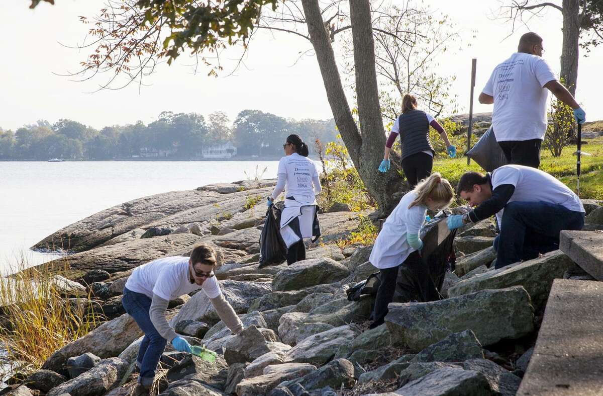 Volunteers from local jewelry stores pick up trash along the waterline at Cove Island Park in Stamford on Sunday.
