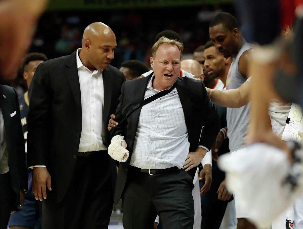 Atlanta Hawks coach Mike Budenholzer, center, is helped to his feet by assistant coach Darvin Ham, left, after he was run over along the sideline during the first half of the team's preseason NBA basketball game against the New Orleans Pelicans Tuesday, Oct. 18, 2016, in Atlanta. Budenholzer, who was already nursing an injured hand, left the game. (AP Photo/John Bazemore)