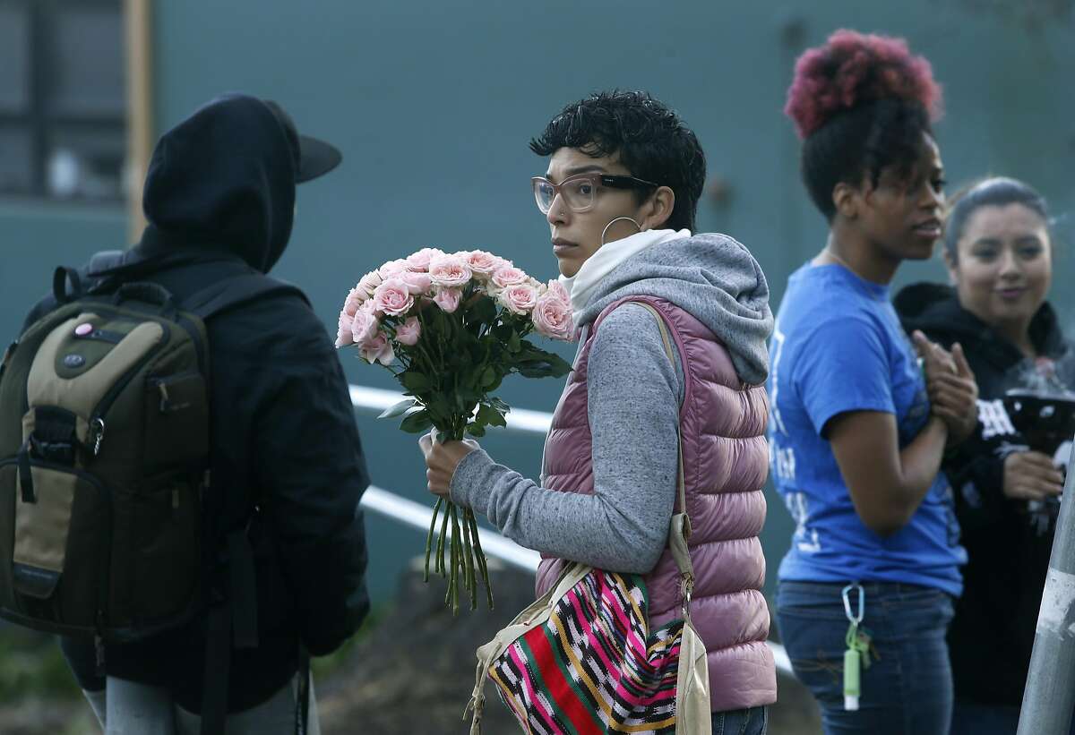 A woman who declined to give her name holds flowers before classes resume at June Jordan School for Equity in San Francisco, Calif. on Wednesday, Oct. 19, 2016, following a shooting that wounded four students after school Tuesday.