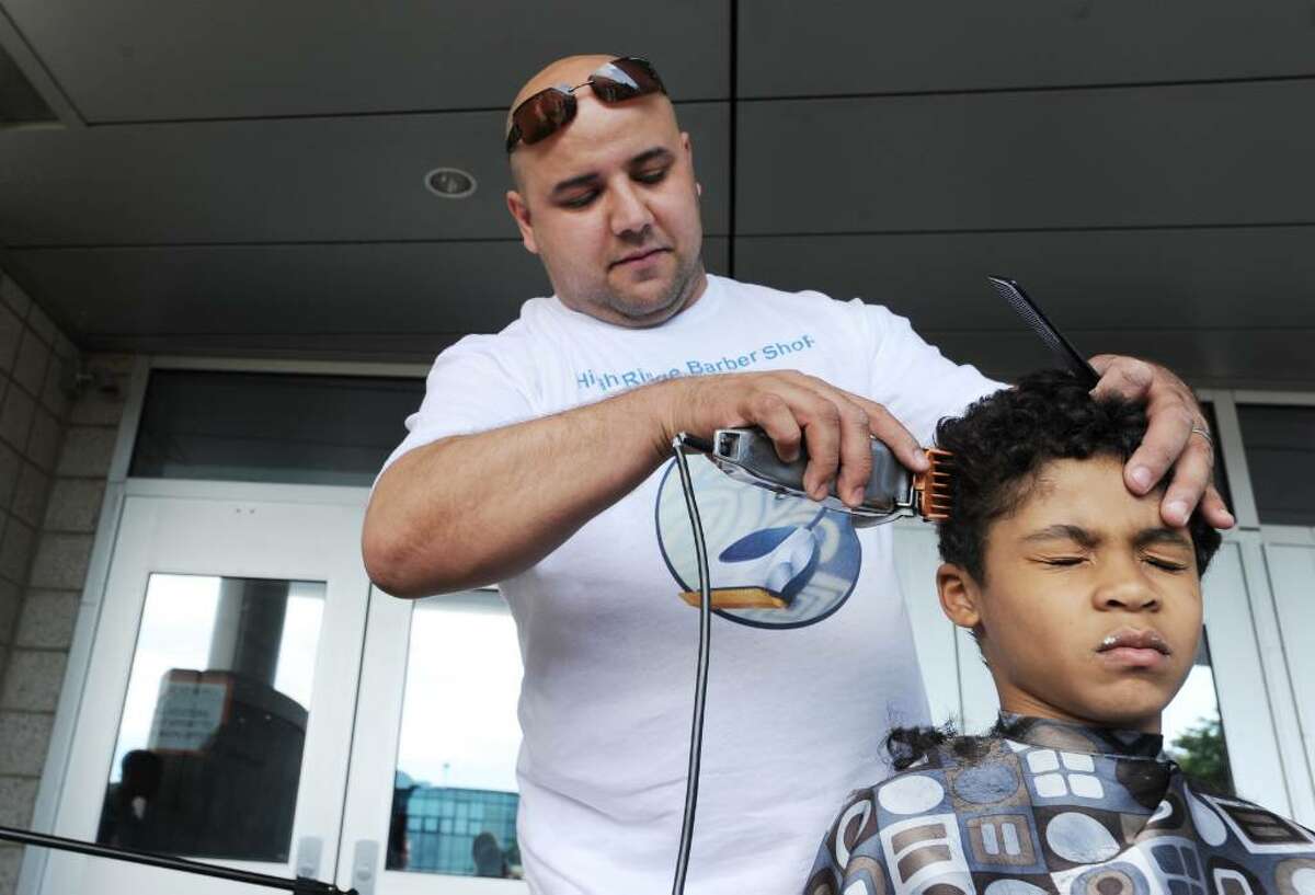 Ethan Colon, 6, has his head shaved by Kalid Mansour, of High Ridge Barber Shop, as students, friends and family at AITE get their hair cut in Stamford, Conn. on Thursday May 13, 2010 to send to an organization that is using human hair to absorb the oil spilled into the Gulf of Mexico when the BP oil rig exploded.