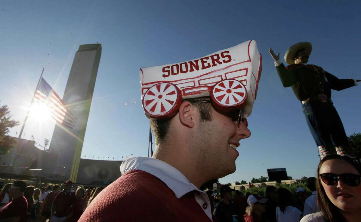FILE - In this Oct. 8. 2016, file photo, Oklahoma fan Grayson Niemeyer wears a hat at the state fair before an NCAA college football game between Texas and Oklahoma in Dallas. Now that the Big 12 has decided to stay at 10 schools, itÂ?’s time to figure out whether or not to split up _ into football divisions. If so, how will the teams be divided? The league, which will keep its round-robin schedule, has to determine who will play in its championship game that returns next season. (AP Photo/LM Otero, File)