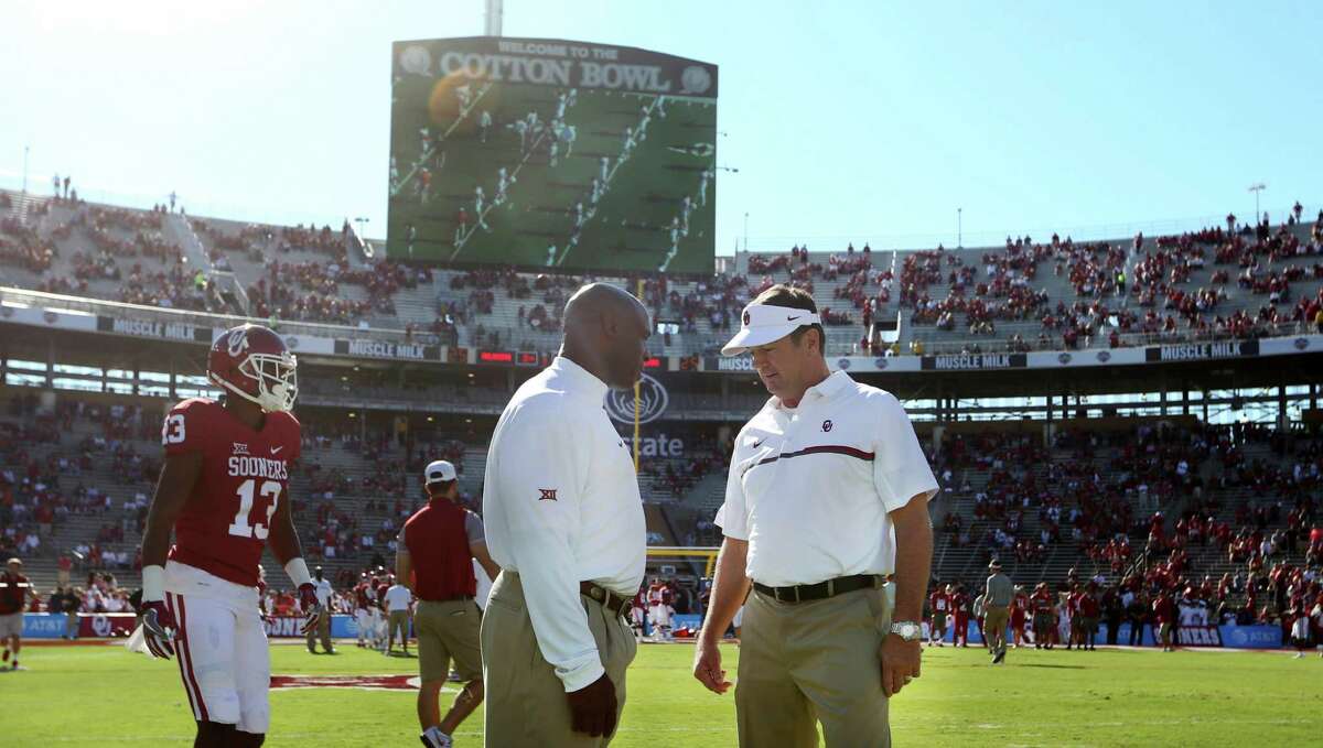 FILE - In this Oct. 8, 2016, file photo, Oklahoma coach Bob Stoops, right, and Texas coach Charlie Strong talk on the field before an NCAA college football game in Dallas. Now that the Big 12 has decided to stay at 10 schools, itÂ?’s time to figure out whether or not to split up _ into football divisions. If so, how will the teams be divided? The league, which will keep its round-robin schedule, has to determine who will play in its championship game that returns next season. (AP Photo/LM Otero, File)