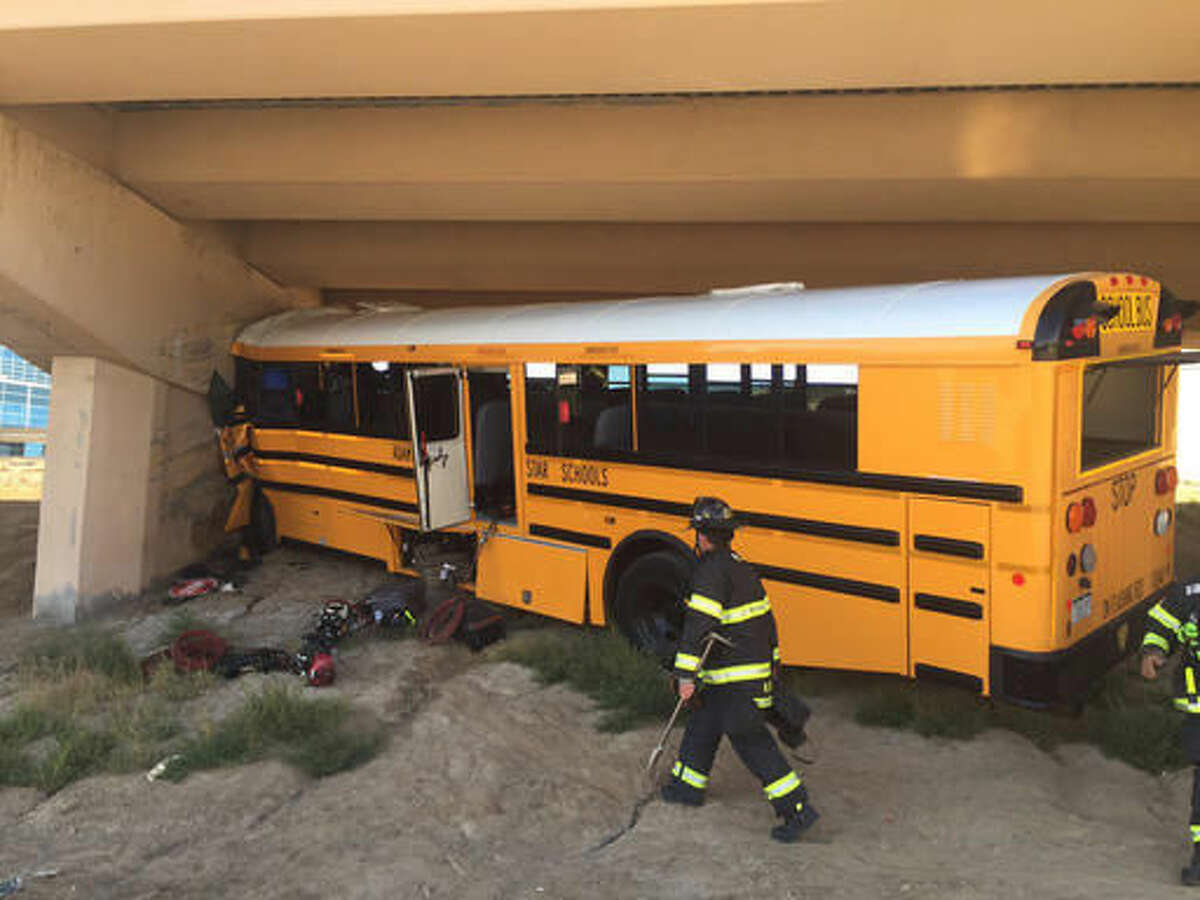 In this Sunday, Sept. 11, 2016 photo provided by the Denver Police Department an officer works at the scene following a crash in Denver. The school bus driver was killed Sunday and several others were injured after the bus veered off a roadway at Denver International Airport and crashed into a concrete pillar, police said. (Denver Police Department via AP)
