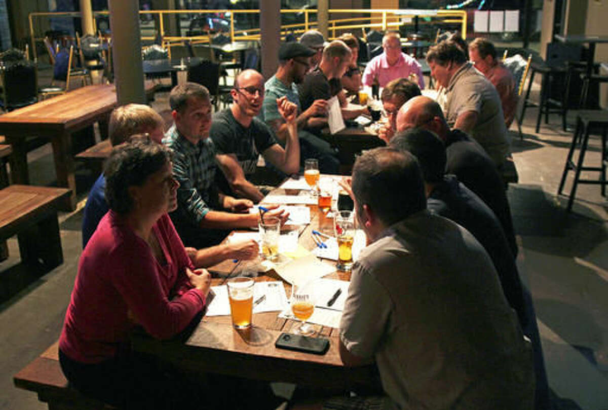 In this Tuesday, Sept. 13, 2016 photo, people gather and talk during a "Jesus & Beer" event at a Waukesha, Wis., pub organized by CollectiveMKE church, which doesn't have a traditional building. The group holds these discussions once a month at Milwaukee and Waukesha bars. It's part of an effort by religious groups nationwide looking for ways to recruit new parishioners, connect with people struggling with their faith or give a different, relaxed outlet to talk religion. (AP Photo/Carrie Antlfinger)