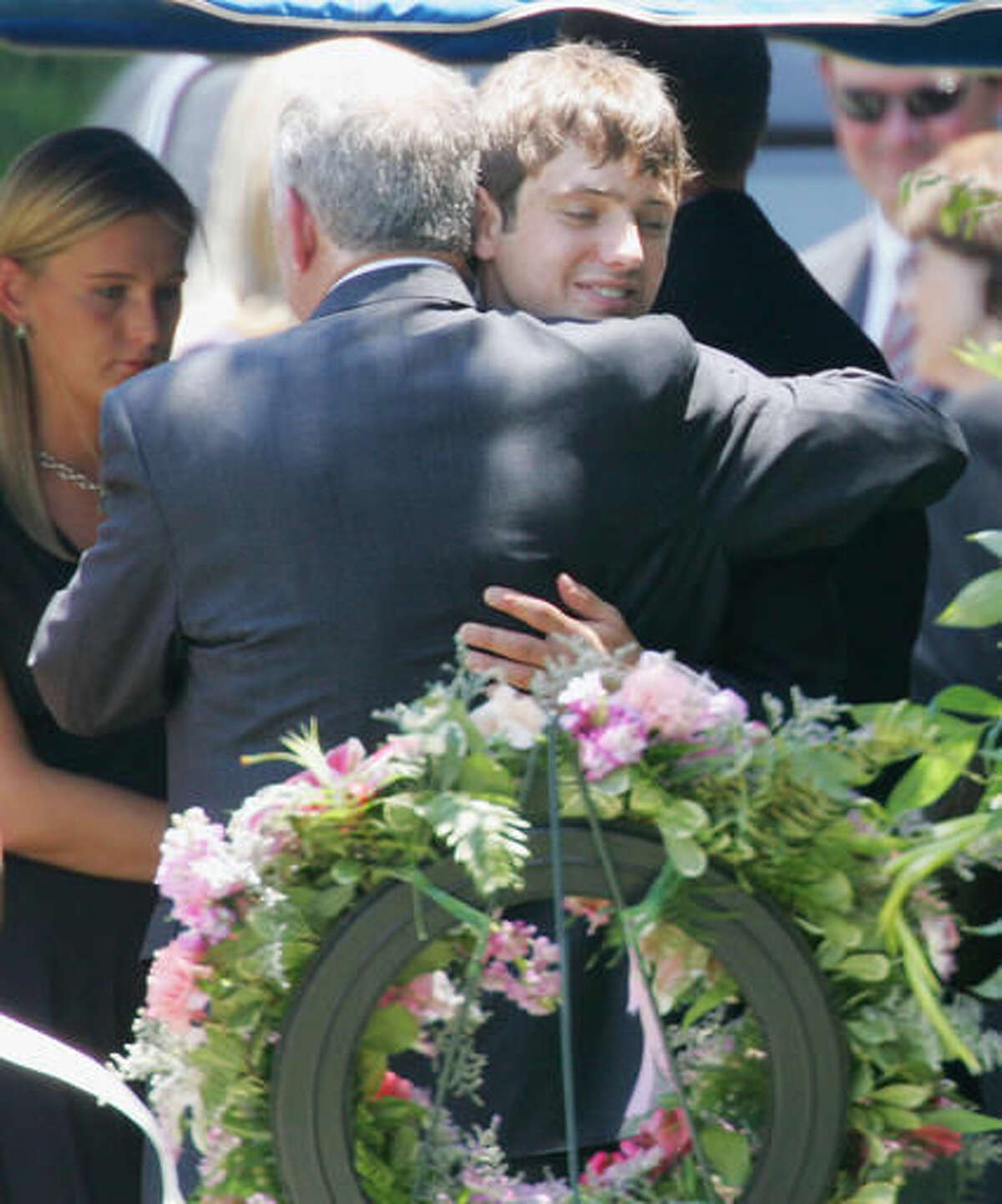 FILE - In this June 29, 2006, file photo, John Ramsey hugs his son, Burke, facing camera, at the graves of his wife, Patsy, and daughter JonBenet, during services for his wife at the St. James Episcopal Cemetery in Marietta, Ga. Burke Ramsey discussed his sister's death with TV's "Dr. Phil" in an interview broadcast on Monday, Sept. 12, 2016. (AP Photo/Ric Feld, File)