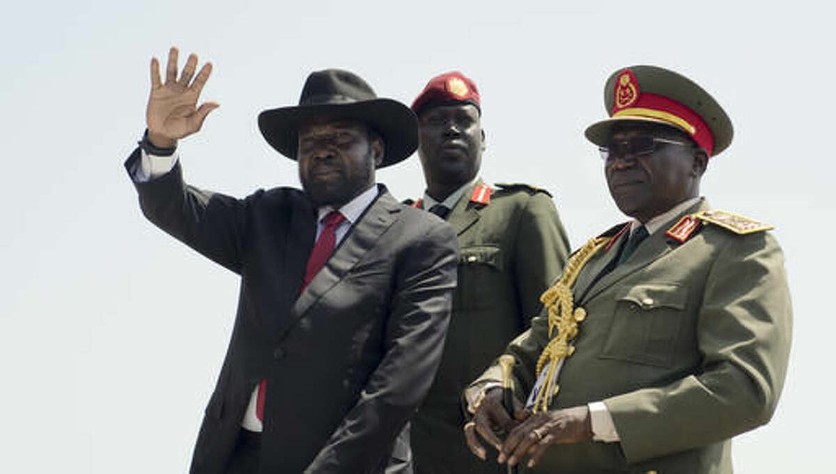 FILE - In this Thursday, July 9, 2015 file photo, South Sudan's President Salva Kiir, left, accompanied by army chief of staff Paul Malong, right, waves during an independence day ceremony in the capital Juba, South Sudan. A confidential U.N. report obtained by The Associated Press on Friday, Sept. 9, 2016 says South Sudan's deadly fighting in July was directed by the highest levels of government, and that leaders are intent on a military solution that worsens ethnic tensions. (AP Photo/Jason Patinkin, File)