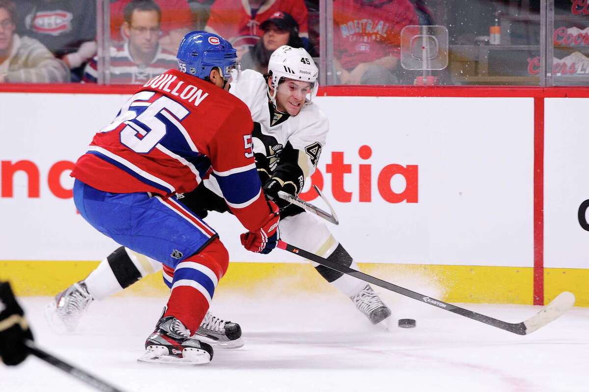 MONTREAL, QC - NOVEMBER 23: Brian Gibbons #49 of the Pittsburgh Penguins passes the puck in front of Francis Bouillon #55 of the Montreal Canadiens during the NHL game at the Bell Centre on November 23, 2013 in Montreal, Quebec, Canada. The Canadiens defeated the Penguins 3-2. (Photo by Richard Wolowicz/Getty Images) ORG XMIT: 181111134 ORG XMIT: MER2016102011450773
