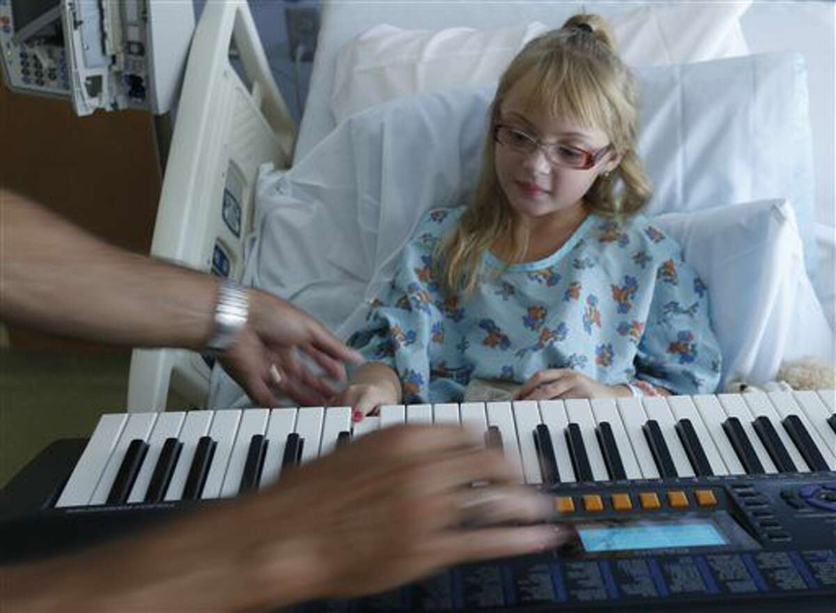 In a Sept. 9, 2016 photo, music therapist David Putano teaches Hannah Gorham, 9, how to play the piano during their first session at the ProMedica Toledo Children’s Hospital in Toledo,Ohio. In ProMedica Toledo Children’s Hospital since Aug. 31 for severe migraines, Hannah was introduced recently to music therapy, a growing practice for hospitalized children and those with developmental or physical disabilities. (Lori King/The Blade via AP)