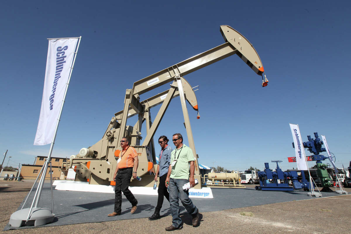 Oil show attendees walk past the Schlumberger booth at the Permian Basin International Oil Show at Ector County Coliseum on Tuesday, Oct. 18, in Odessa, Texas. (Jacob Ford/Odessa American via AP)