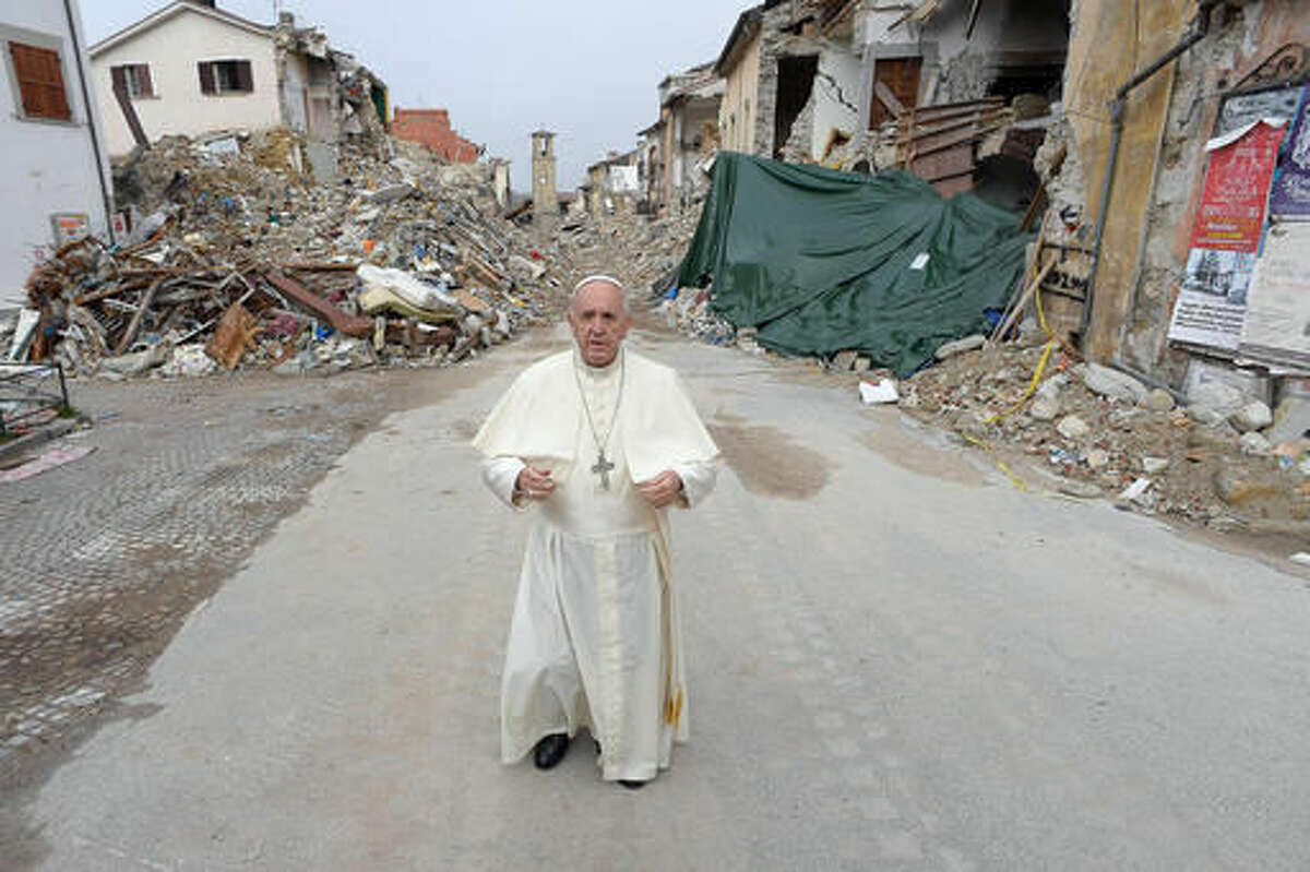 Pope Francis stands in front of rubble, with the standing bell tower in the background, of the quake-struck town of Amatrice, Italy, Tuesday, Oct. 4, 2016. Francis had made clear his intentions to visit the August quake-stricken zone in central Italy, but without announcing a date, indicating that he wanted to go alone "to be close to the people." (L'Osservatore Romano/ Pool Photo via AP)