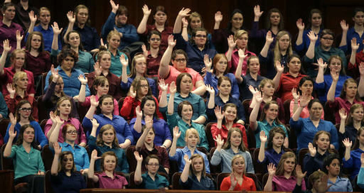 FILE - In this April 2, 2016, file photo, members of the combined Choir from BYU-Idaho raise their hands during a sustaining vote at the two-day Mormon church conference in Salt Lake City. Mormons gather for a twice-yearly conference to hear spiritual guidance from top leaders during a testy presidential election and as society grapples with issues of race and sexuality. (AP Photo/Rick Bowmer, File)