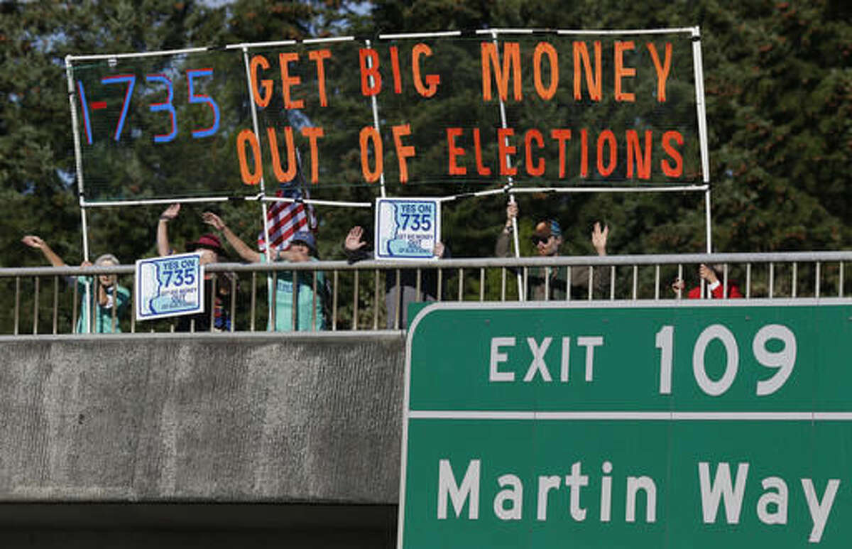 In this photo taken Sept. 22, 2016, supporters of Initiative 735 hold a banner above the I-5 freeway during the evening commute in Lacey, Wash. Proponents of the statewide ballot initiative want to get big money out of politics by backing a federal constitutional amendment that says free speech in the form of political contributions belongs to people, not corporations. Opponents of the measure say the government shouldn’t limit the First Amendment. (AP Photo/Ted S. Warren)