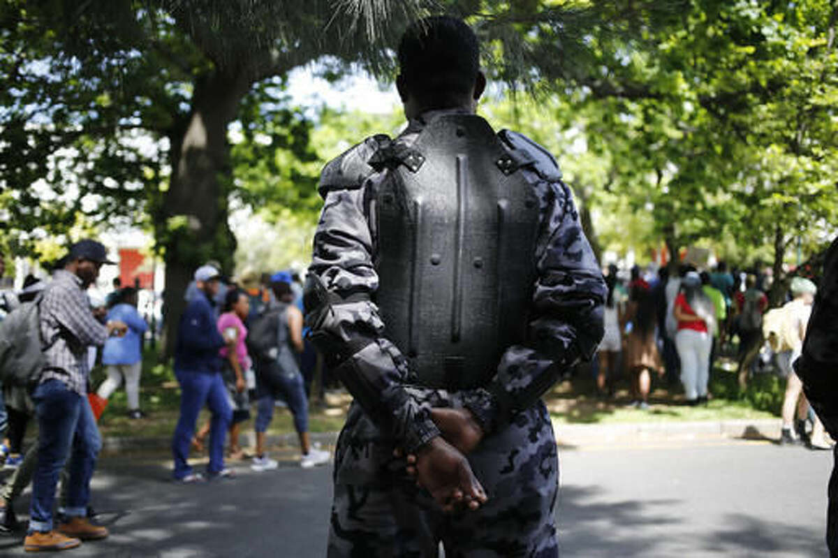 A security guard patrols as students from the University of Cape Town protest in Cape Town, South Africa, Tuesday, Oct. 4, 2016, demanding free university education. President Jacob Zuma has said the recent protests at some South African universities have caused about $44 million in property damage and threaten to sabotage the country's system of higher education. (AP Photo/Schalk van Zuydam)