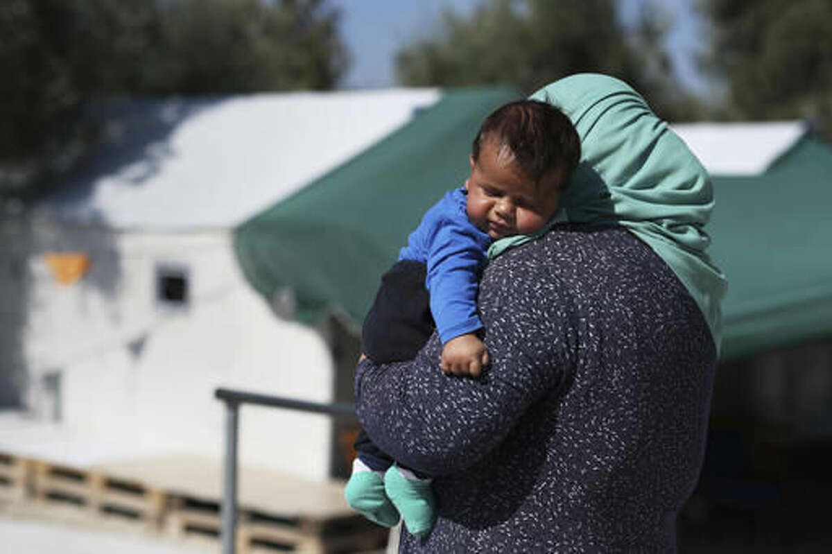 A woman carries her baby at the Kara Tepe camp for refugees and other migrants in Lesbos island, Greece, on Thursday, Oct. 6, 2016. ﻿More than a million migrants and refugees crossed through Greece and on to other EU countries since the start of 2016, while over 60,000 have been stranded in the country since the EU-Turkey deal took effect and the Balkan transit route north was closed. (AP Photo/Petros Giannakouris)