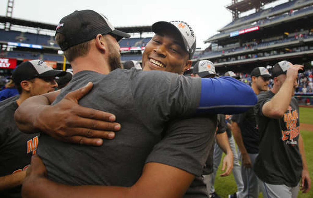 New York Mets relief pitcher Jeurys Familia, right, is embraced by a teammate after the Mets defeated the Philadelphia Phillies 5-3 in a baseball game securing a wildcard playoff slot, Saturday, Oct. 1, 2016, in Philadelphia. (AP Photo/Laurence Kesterson)
