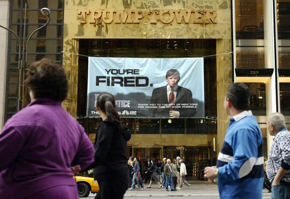 FILE - In this Saturday, March 27, 2004 file photo, passersby look at a sign advertising the reality television show, "The Apprentice," displayed at the entrance to the Trump Tower building in New York. Donald Trump's development firm was issued summonses by the city because it did not have the proper permits for the giant banner. In his years on the show, Trump repeatedly demeaned women with sexist language, according to show insiders who said he rated female contestants by the size of their breasts and talked about which ones he'd like to have sex with. (AP Photo/Bebeto Matthews)