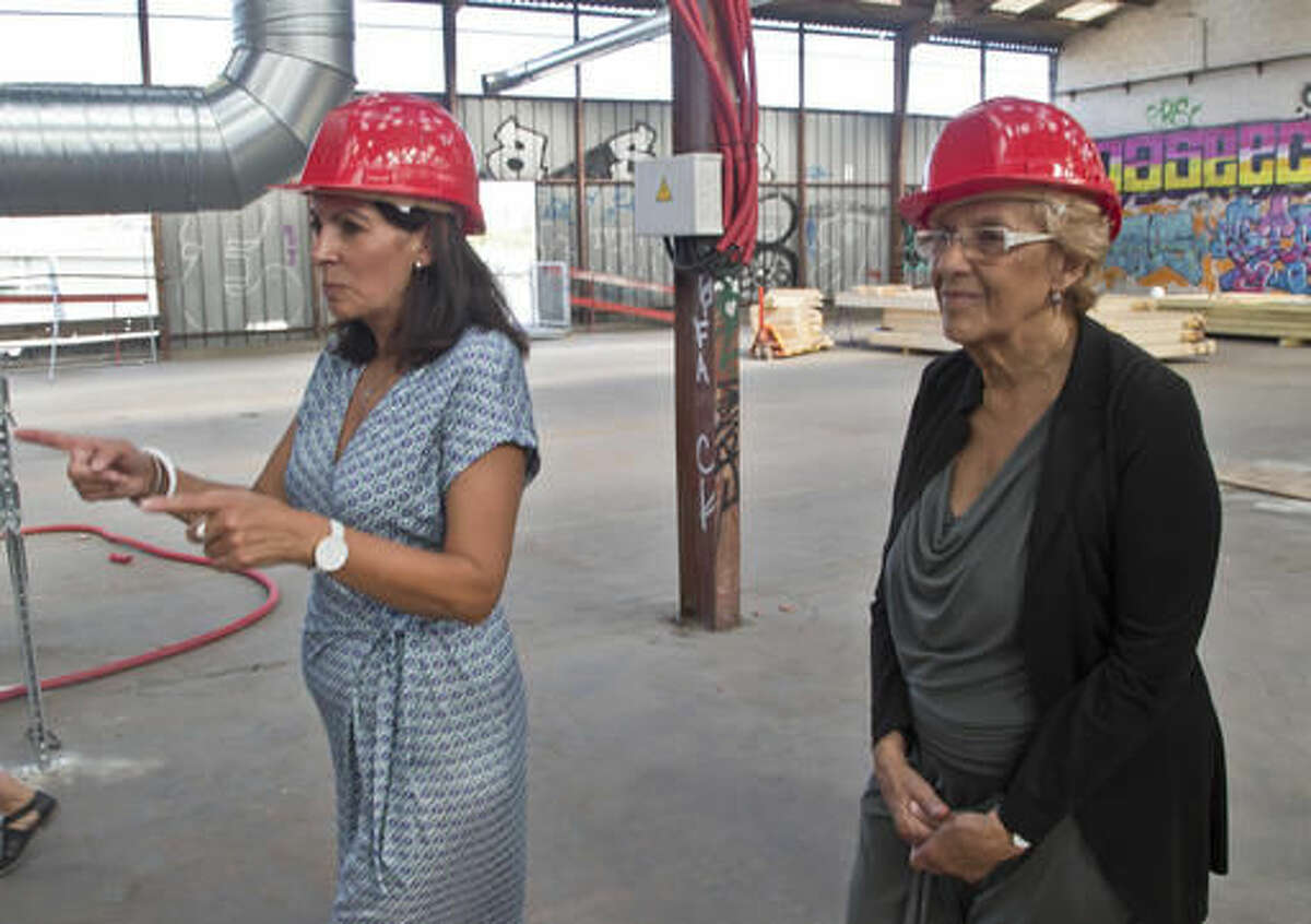 Mayor of Paris Anne Hidalgo, left, points the direction to Mayor of Madrid Manuela Carmena as they visit a construction site of a reception center for migrants in Paris, Monday, Sept. 12, 2016. A new reception center for migrants in the French capital, is scheduled to open next month, in an unusual and controversial effort to cope with Europe's migrant crisis. (AP Photo/Michel Euler)