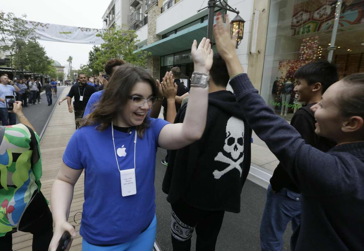 Apple sales associates cheer customers waiting in line for the latest versions of the iPhone, before the opening day of sales of the iPhone 5s and iPhone 5C at the Apple store at the Americana at Brand mall in Glendale, Calif., Friday, Sept. 20, 2013. (AP Photo/Damian Dovarganes)