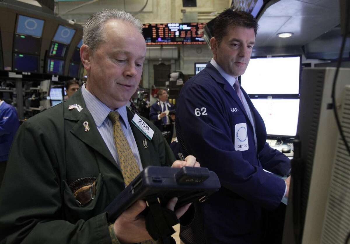Trader James Riley, left, and specialist David Haubner work on the floor of the New York Stock Exchange on Wednesday. Stocks edged lower early Wednesday after investors saw signs that economies could be slowing down in both the West and China. (AP Photo/Richard Drew)