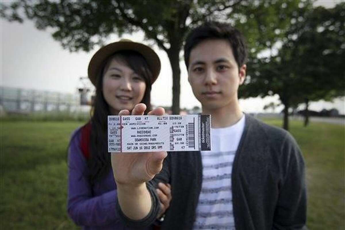 Jeongmi Lee and her boyfriend Mark Lee show their tickets as they leave Downsview Park after a stage collapsed prior to a Radiohead concert in Toronto, Saturday, June 16, 2012. The top of a stage being set up for a concert collapsed, killing one of the stage workers preparing for the event which was canceled. (AP Photo/The Canadian Press, Toronto Star, Tara Walton)