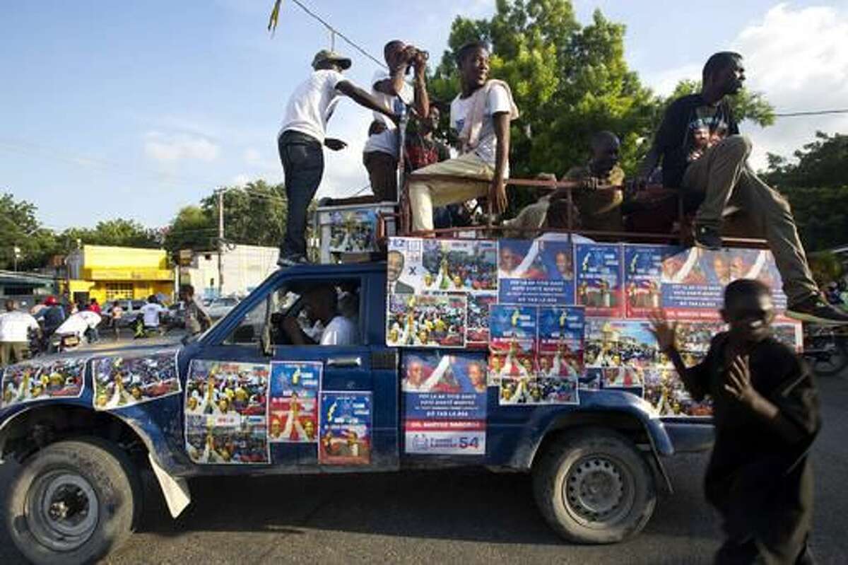 In this Sept. 21, 2016 photo, a truck is covered with campaign signs in favor of Haiti's former President Jean-Bertrand Aristide and presidential candidate Maryse Narcisse, of the Fanmi Lavalas political party, during a campaign event in Port-au-Prince, Haiti. While it’s easy to find hardcore Lavalas supporters in neighborhoods that were once Aristide strongholds, roughly a third of Haiti’s population is younger than 15 and only know his image from placards or paintings sold on roadsides. Haiti will hold elections on Oct. 9. (AP Photo/Dieu Nalio Chery)