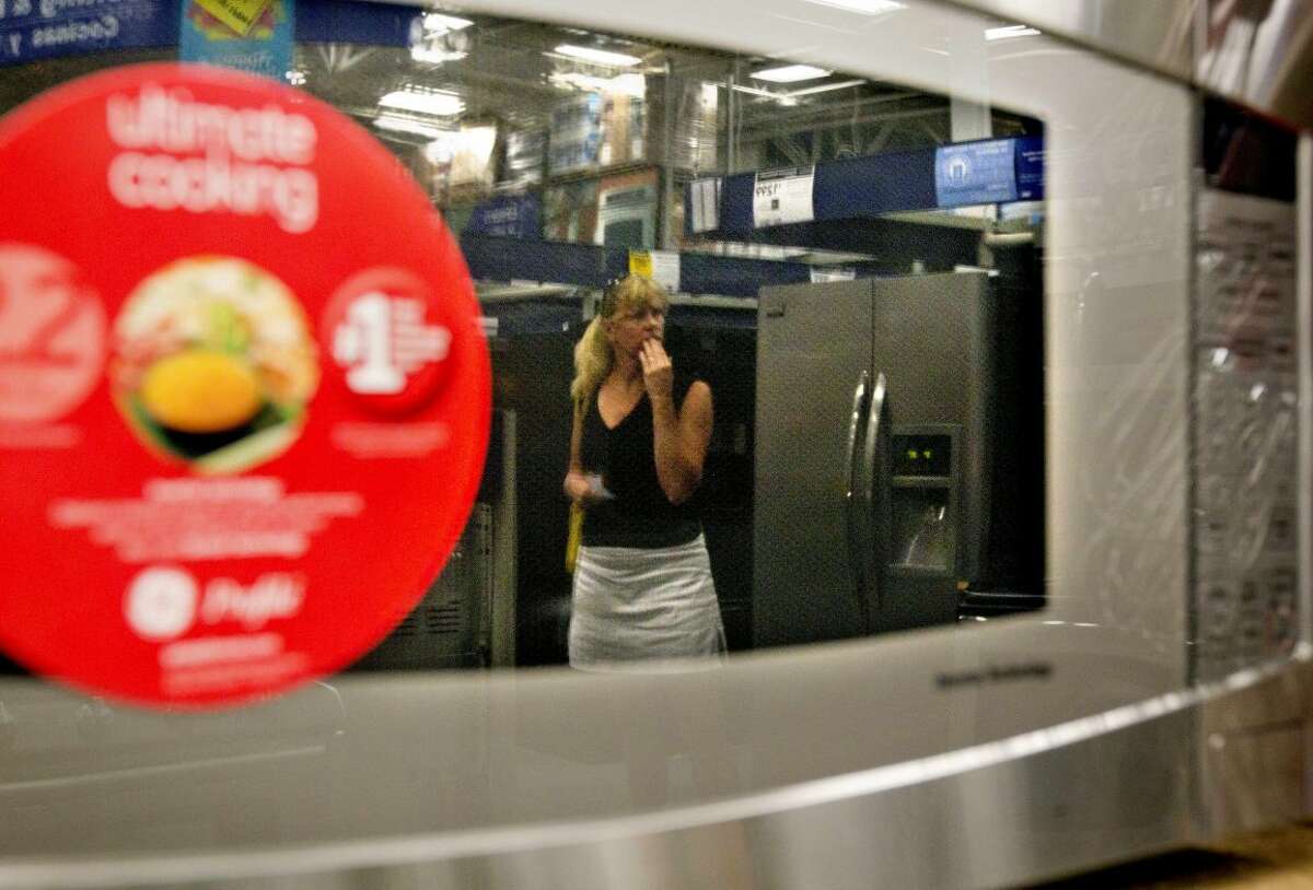 In this June 19, 2012 photo, a shopper is reflected in a microwave oven on display on a showroom floor at Lowe's store in Atlanta. Consumer confidence fell in June for the fourth month in a row as lingering worries about the economy outweighed relief at the gas pump, according to a private research group. (AP Photo/David Goldman)