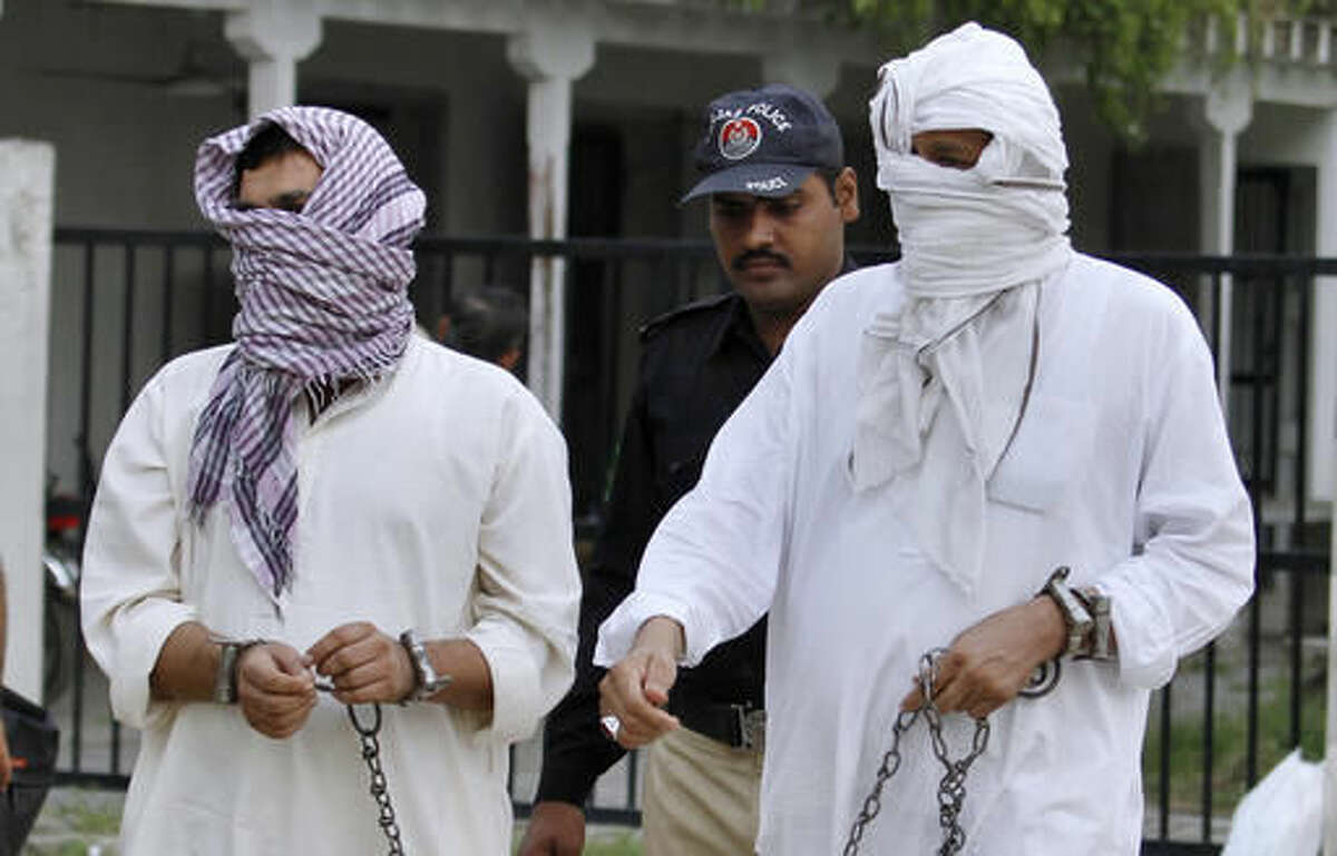 FILE - In this Friday, Sept. 23, 2016 file photo, a Pakistani police officer escorts father Mohammad Shahid, right, and ex-husband Mohammad Shakeel of slain British-Pakistani woman Samia Shahid to a court in Jhelum, Pakistan. A defense lawyer says Tuesday, Sept. 27, 2016 that Pakistani court has opened the trial against the father and ex-husband of a British woman over her alleged rape and murder in the name of so-called honor. (AP Photo/Anjum Naveed, File)