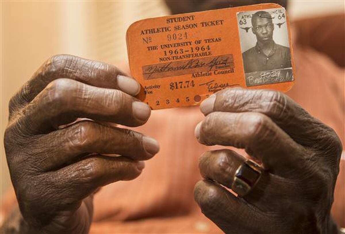 In this Wednesday, Sept. 7, 2016 photo, Nathaniel Bradford poses with his Student Athletic Season Ticket from 1963-1964 at his home in Austin, Texas. Nathaniel Bradford was one of the first black undergraduates at the University of Texas, who enrolled 60 years ago. Bradford will be honored at the university with a series of activities. (Ricardo B. Brazziell/Austin American-Statesman via AP)