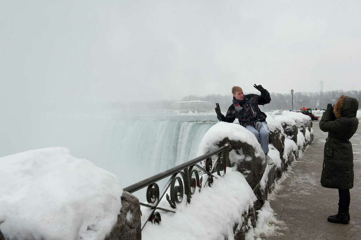 An adventuresome tourist flashes two hopeful peace signs as his photograph is taken near the arch of the horseshoe at Niagara Falls.