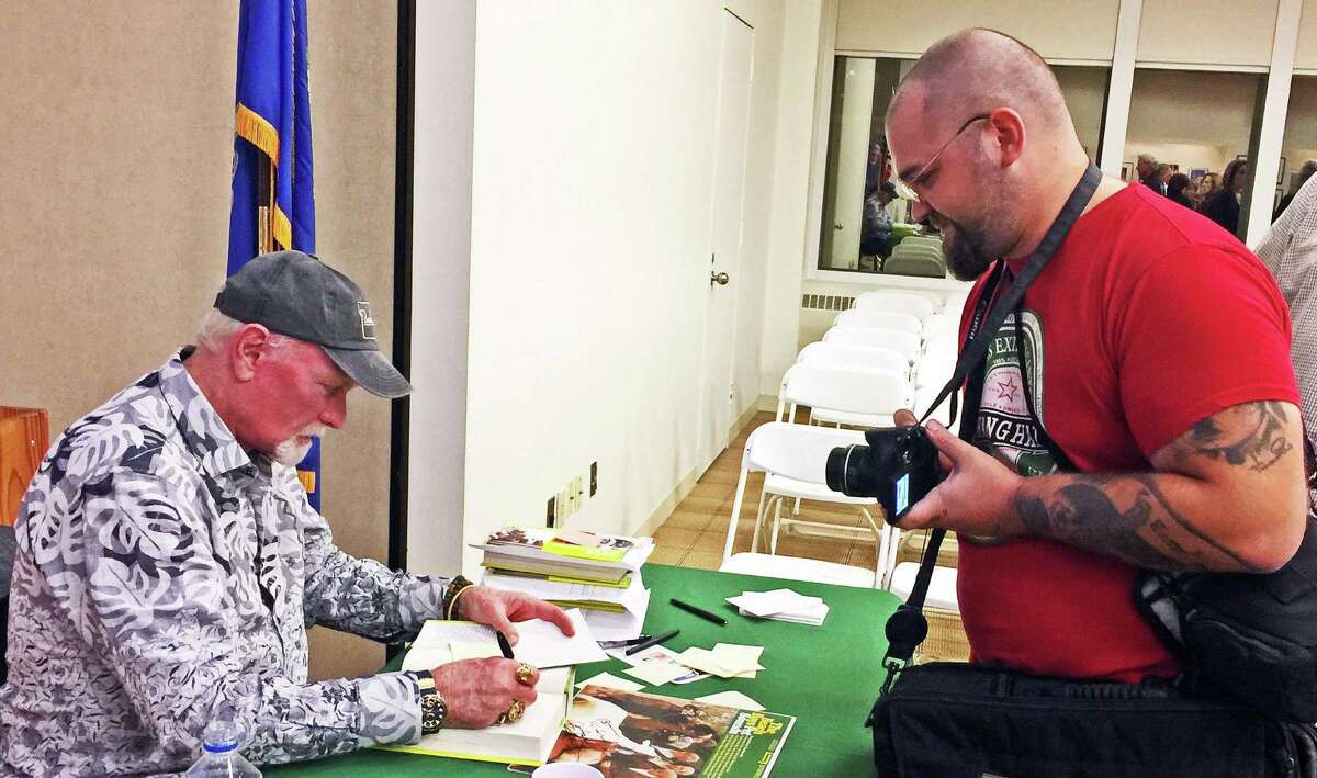 Beach Boy Mike Love, left, signs a copy of his book “Good Vibrations: My Life as a Beach Boy” for Will Bozarth, 29, of Deptford, N.J., at Ferguson Library in Stamford, Conn., after Love’s address about “Civility in Music” on Oct. 14, 2016. Bozarth brought a vinyl copy of the Beach Boys’ “Pet Sounds” album (on table) that had been signed by fellow band founders Brian Wilson and Al Jardine last month.