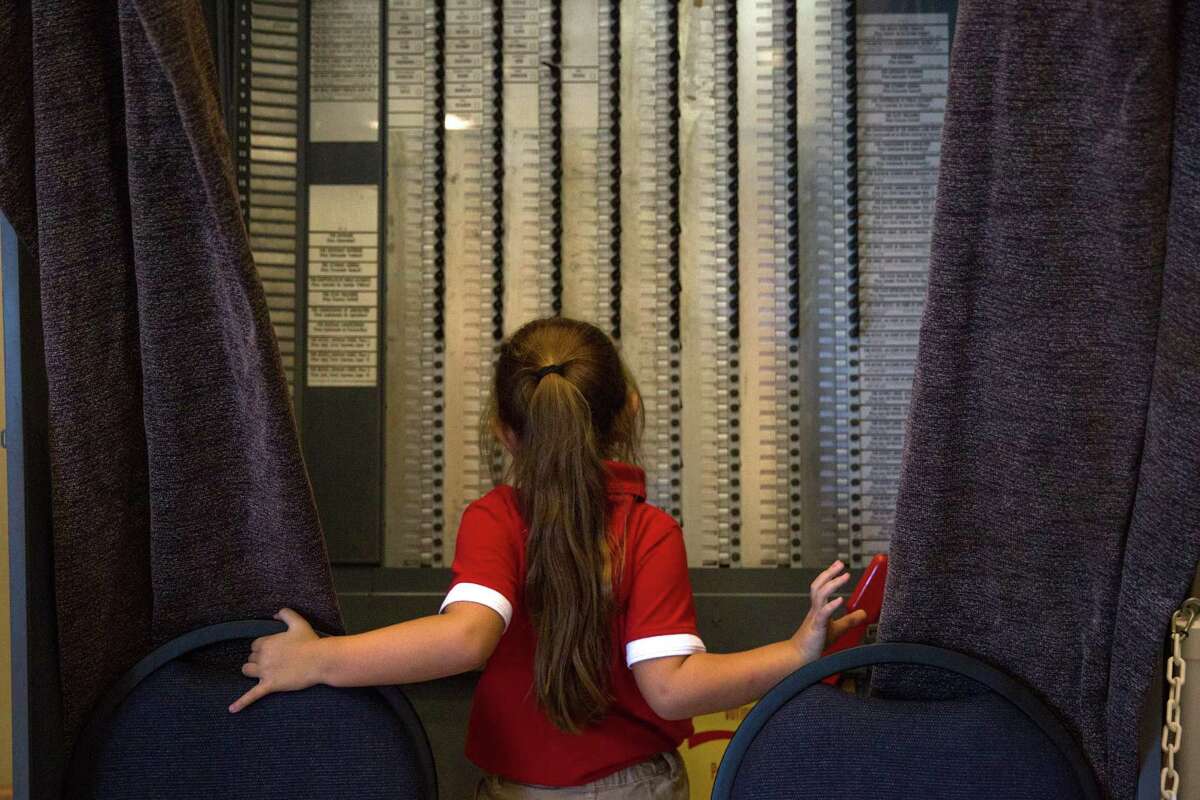 San Antonio, Texas -- October 11, 2016 -- Mia Brown, 6, inspects an old voting booth at the Bexar Country Elections Office while her parents register to vote. Ray Whitehouse / for the San Antonio Express-News