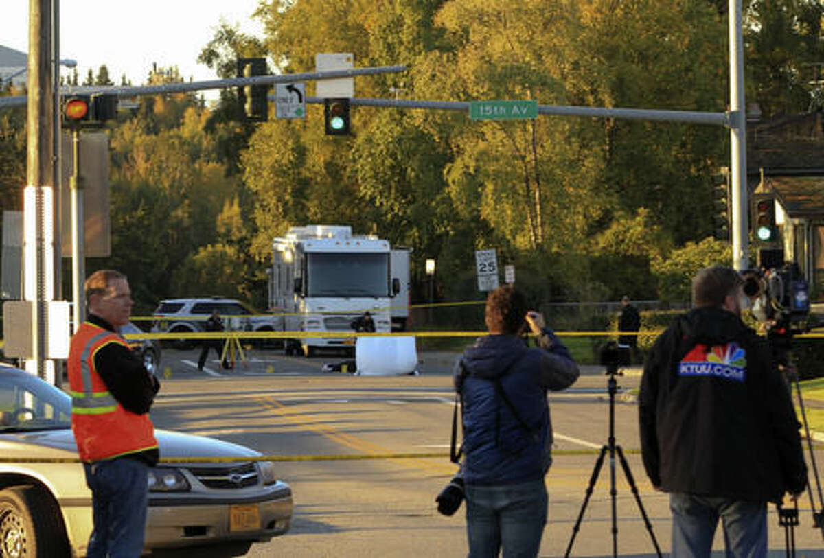 A photographer and videographer stand behind police lines as Anchorage police process a crime scene near two downtown schools in which a man was found fatally shot on Tuesday, Sept. 13, 2016, in Anchorage, Alaska. The intersection at 15th Avenue and C Street borders Central Middle School and is two blocks from Chugach Optional Elementary School. The shooting occurred before the schools opened but the schools were closed for the day. (AP Photo/Dan Joling)