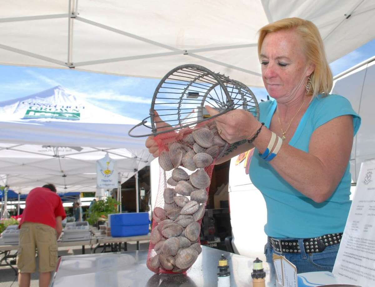 Laurie Popadic of Pepe's Cream of the Crop Shellfish Farm of Milford, Conn., loads littleneck clams into a plastic mesh bag for sale during the opening day of the Greenwich Farmers Market in the Horseneck public parking lot, Greenwich, Saturday morning, May 15, 2010. Popadic said a bag of 100 littleneck clams goes for $40.