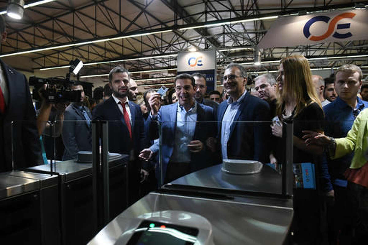 Greek Prime Minister Alexis Tsipras, center, shows off a ticket issued by a ticket machine during the first day of the 81th Thessaloniki International Trade Fair, at the northern Greek city of Thessaloniki, on Saturday, Sept. 10, 2016. Greece, which depends on a bailout cash before the end of October to stay afloat, has recently fallen short of reform commitments, stoking concerns of a flare-up in the country's debt crisis. (AP Photo/Giannis Papanikos)