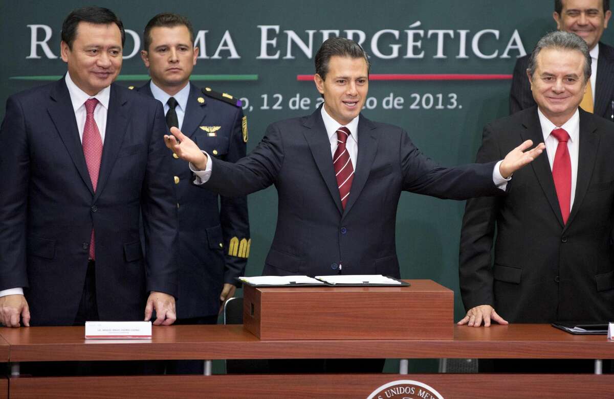 In this Aug. 12, 2013 file photo, Mexico's President Enrique Pena Nieto, center, greets the audience flanked by the Interior Secretary Miguel Angel Osorio Chong, left, and Energy Secretary Pedro Joaquin Coldwell during the ceremony to announce his proposal that would allow private firms to participate in the oil industry in Mexico City. Legislators from Mexico's two pro-energy reform political parties say they support constitutional changes to allow the government to grant licenses and share oil and profits with giants such as Exxon or Chevron. (AP Photo/Eduardo Verdugo, File)