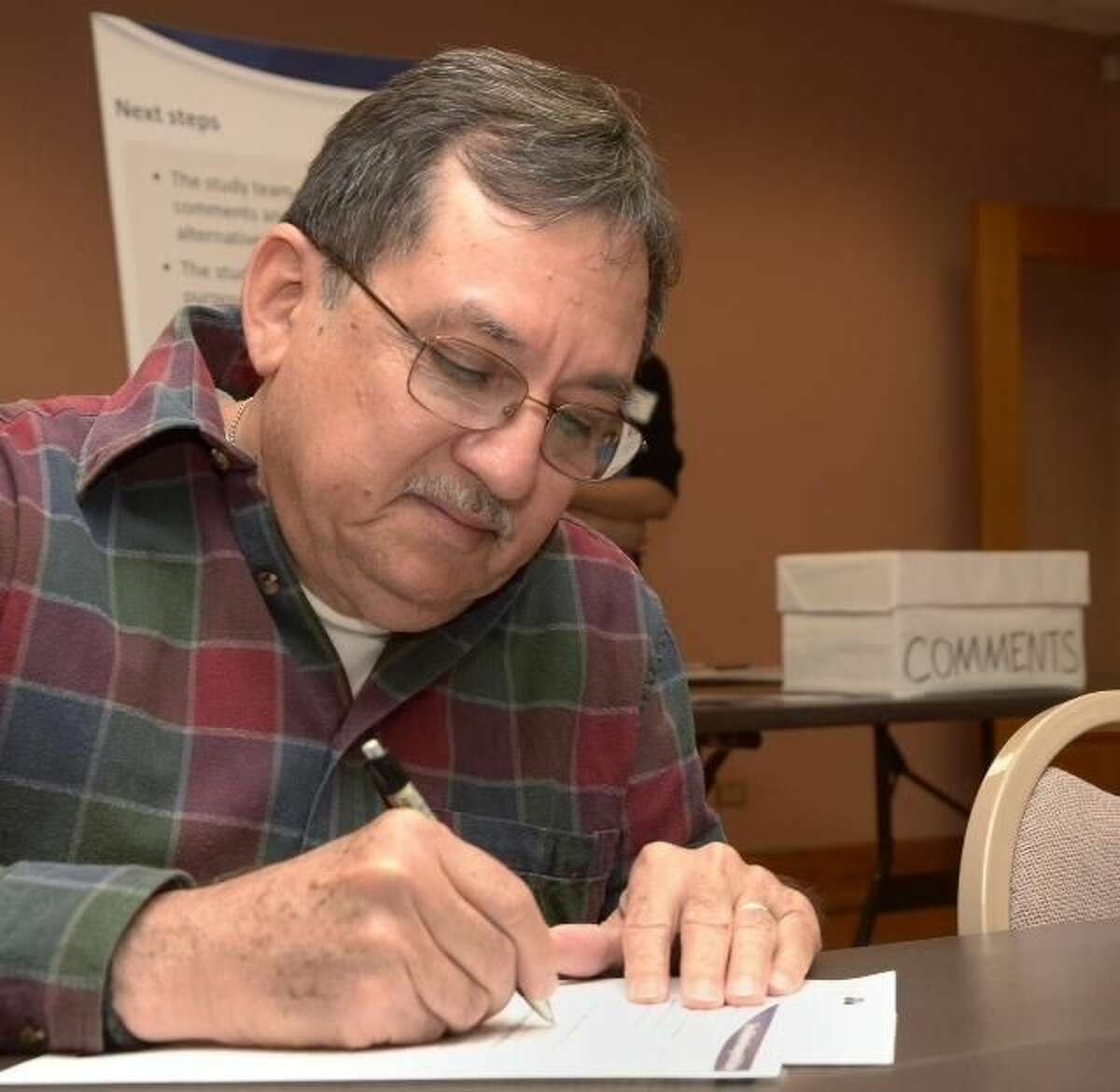 Laredoan Juan Medina writes his comments on the proposed passenger rail line at a town hall Wednesday evening at the TxDOT offices in Laredo. Officials from the city, Nuevo Laredo as far as Monterrey, Nuevo León, Mexico, contributed to the discussion.(Photo by Cuate Santos/Laredo Morning Times)