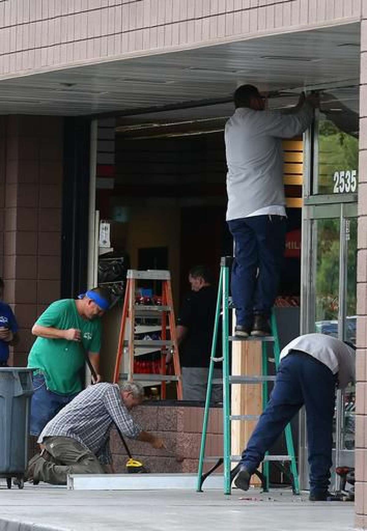 Construction workers continue cleaning up in front of a QuickTrip store hours after a driver plowed into two police officers Tuesday, Sept. 13, 2016, in Phoenix. Police said Marc LaQuon Payne, 44, apparently drove his vehicle at the officers before hitting a patrol car and crashing into the front of the store around 2 a.m. Tuesday. (AP Photo/Ross D. Franklin)