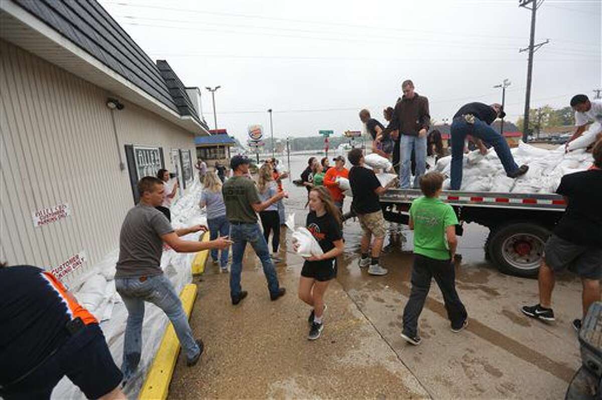 Volunteers work to build a sandbag wall at the Alley Cuts on Main building along West Main Street, Friday, Sept. 23, 2016 in Manchester, Iowa. Authorities in several Iowa cities were mobilizing resources Friday to handle flooding from a rain-swollen river that has forced evacuations in several communities upstream, while a Wisconsin town was recovering from storms now blamed for two deaths. (Jessica Reilly/Telegraph Herald via AP)