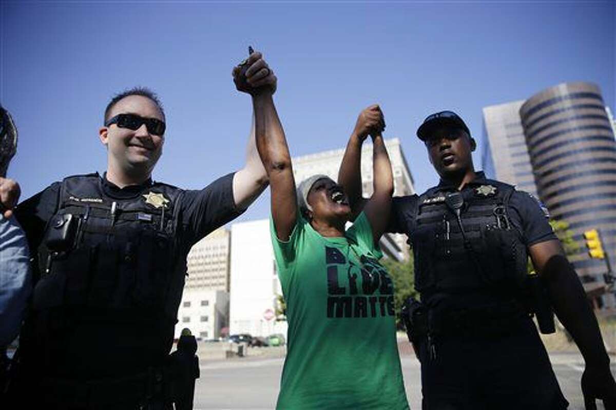 In this Thursday, Sept. 22, 2016 photo, Angie Pitts, of Tulsa, holds hands with Tulsa Police officers while protesting the death of Terence Crutcher, who was shot by police, in front of the Tulsa Country Courthouse, in Tulsa, Okla. (Mike Simons/Tulsa World via AP)